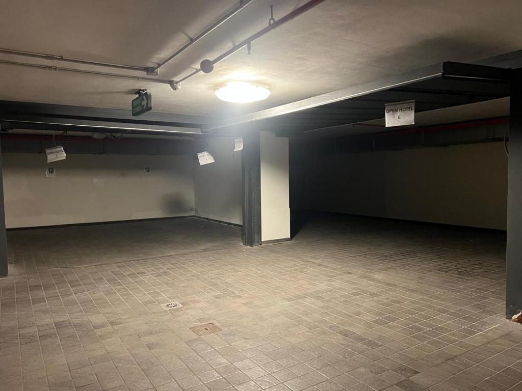 Tukša autostāvvieta ar apgaismojumu un zīmēm, kas norāda uz viesnīcu.