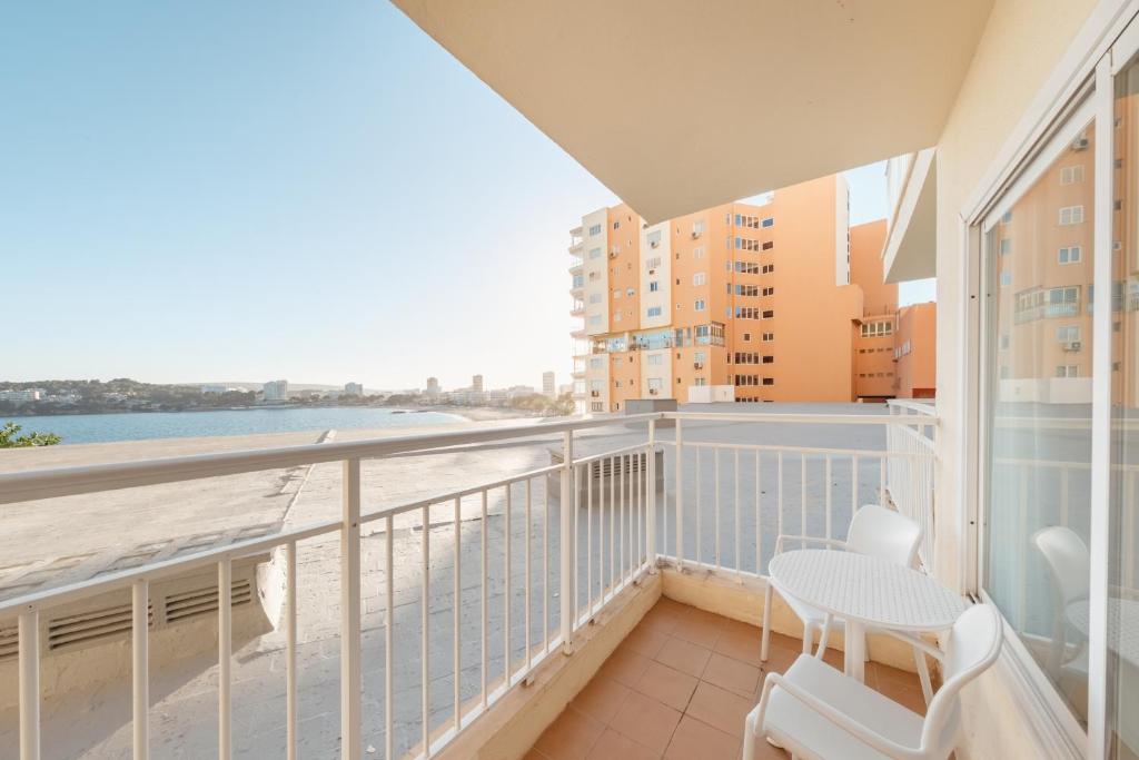 Terase ar baltām mēbelēm, skats uz ūdeni un modernu dzīvojamo ēku fons. Ideāla vieta relaksācijai un atpūtai.