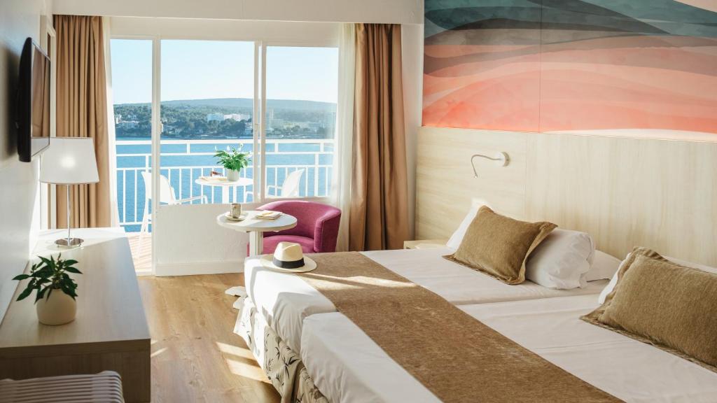 Mūsdienīgs viesnīcas numurs ar divām gultām, kur logā paveras skats uz jūru un terasi. Interjerā izmantoti silti toņi, pieejams arī mazs galds un krēsls.