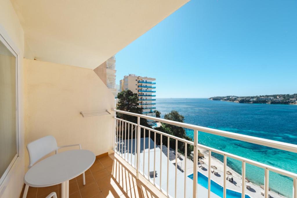 Skats no balkona uz jūru un apkārtējiem viesnīcu kompleksiem, skaidrā laikā ar zilo ūdeni un peldbaseinu zemāk.