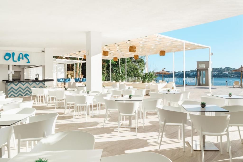 Mūsdienīgs restorāns ar baltām mēbelēm un skatu uz jūru, piedāvā relaksējošu atmosfēru. Restorāna nosaukums "OLAS" ir redzams virs bāra zonas.