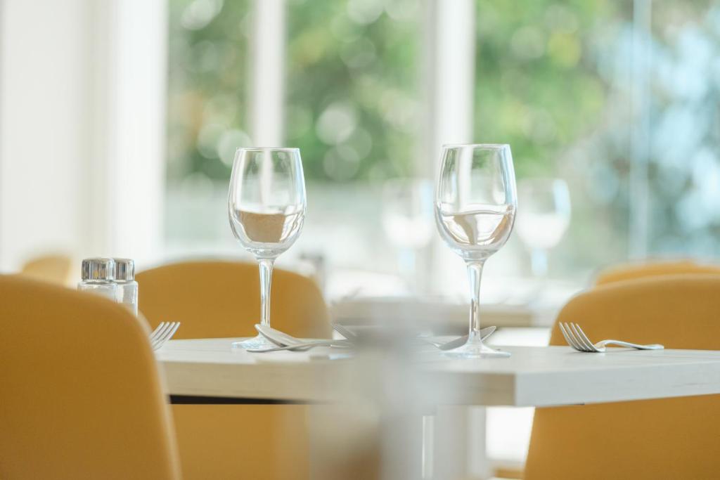 Eleganta galda uzstādīšana ar glāzēm un piederumiem, kas radīta mājīgas atmosfēras sajūtai restorānā.