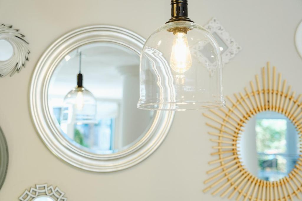 Skaista gaismas spuldze zem stikla kupola, kas atspoguļojas dažādos spoguļos uz sienas, radot modernu un stilīgu interjeru.