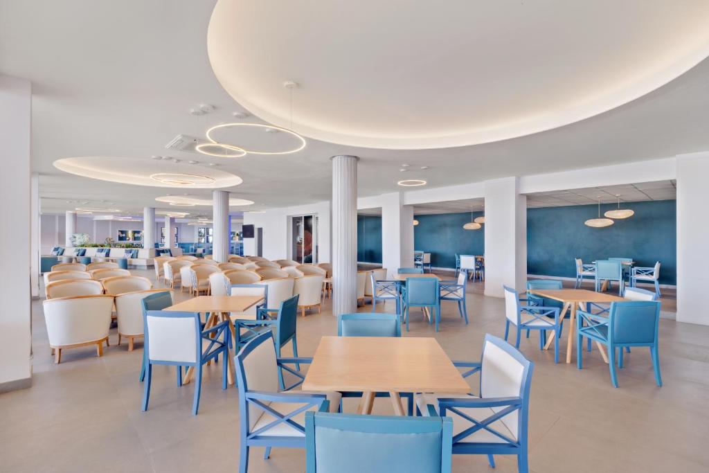 Mūsdienīga restorāna iekārtojums ar zilu un baltu krāsu shēmu, ērtām krēsliem un galdiem, kā arī plašām telpām un modernām apgaismojuma sistēmām.