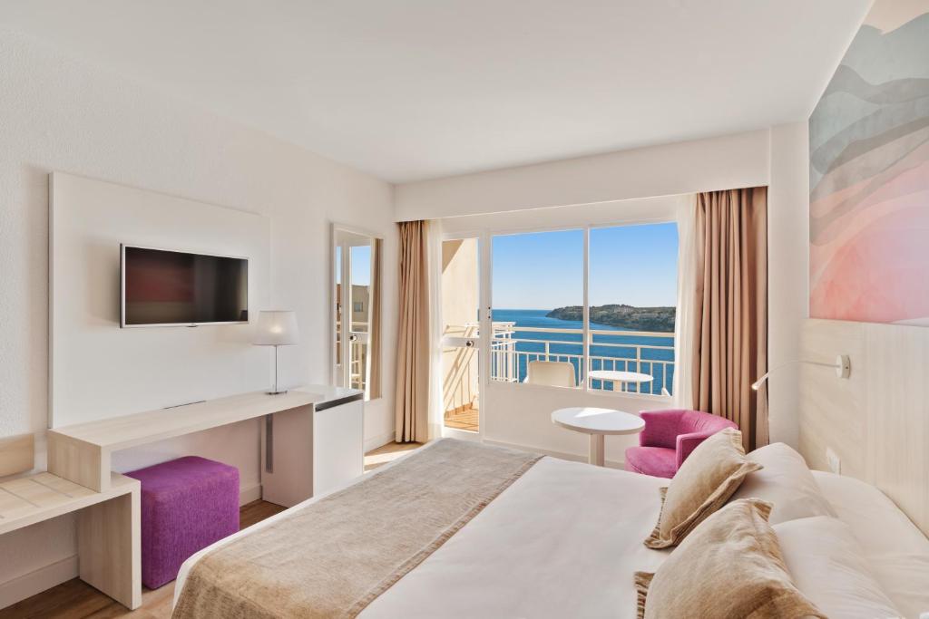 Mūsdienīgs viesnīcas numurs ar skatu uz jūru, iekārtots ar gultu, televizoru un ērtu sēdvietu. Interjerā ir gaišas krāsas un elegants dizains.