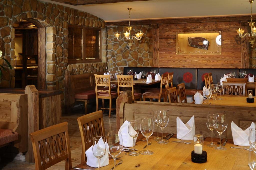 Kafejnīcas interjers ar akmens un koka elementiem, eleganti galdi un krēsli, sagatavoti viesu uzņemšanai. Siltā atmosfērā redzami stikla trauki un dekoratīvas detaļas.