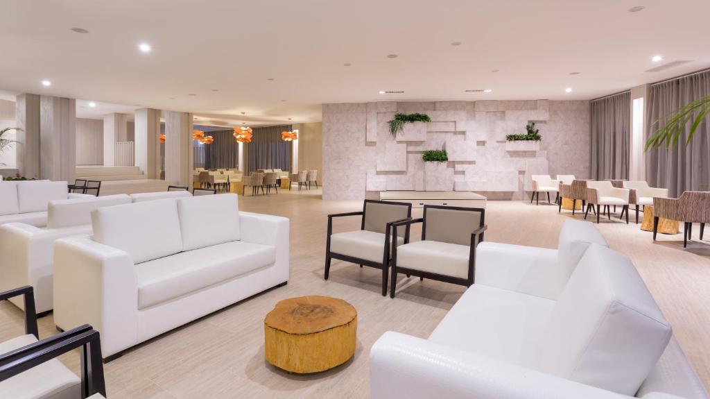 Mūsdienīgs viesnīcas vestibilis ar baltām mēbelēm, koka akcentiem un gaišām krāsām. Interjers veidots ar minimālistisku pieeju, radot relaksējošu atmosfēru.