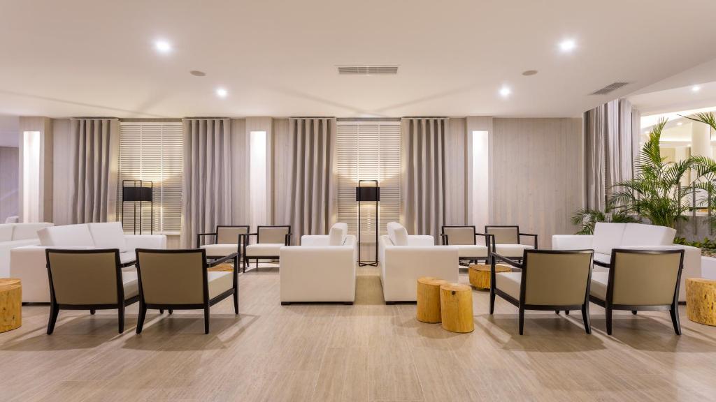 Mūsdienīgs viesnīcas atpūtas telpas iekārtojums ar baltām mēbelēm, koka elementiem un relaksējošu atmosfēru. Ideāla vieta atpūtai un sociālām aktivitātēm.