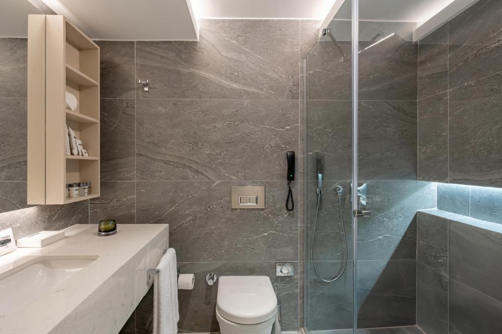 Mūsdienīga vannas istaba Bergiz Hotels & Resort Kemer ar pelēkiem akmens elementiem.