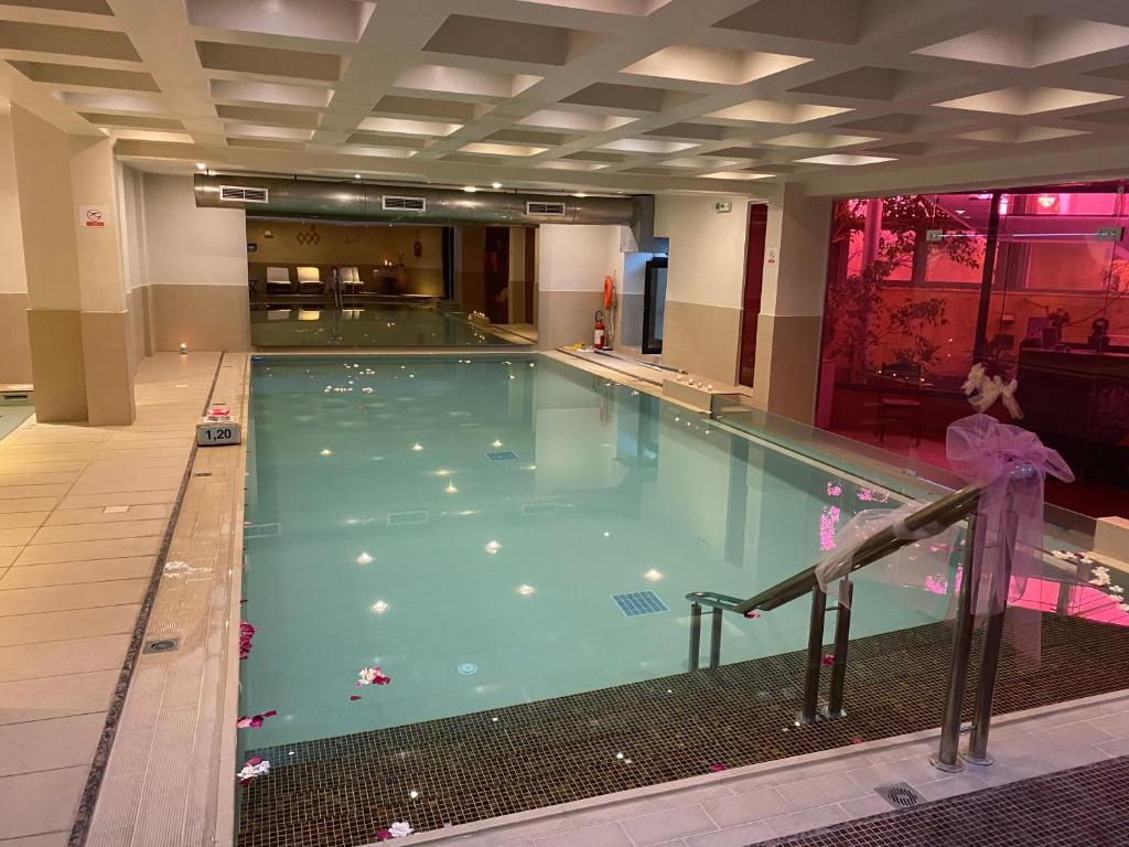 Iekštelpu peldbaseins ar mierīgu atmosfēru, dekorēts ar ziedlapiņām un apgaismojumu, kas rada relaksējošu noskaņu.