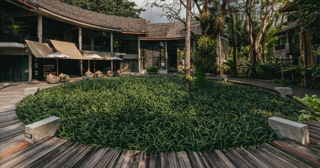 Mūsdienīgs viesnīcas komplekss ar zaļām zonām un koka terasi, kas ieskauj apaļu zālienu. Apkārtējā daba un arhitektūra veido harmonisku un relaksējošu atmosfēru.