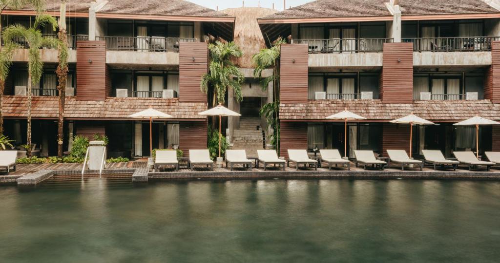 Mūsdienīgs kūrorta komplekss ar baseinu un sauļošanās krēsliem, apkārt palmām un zaļumiem, radot relaksējošu atmosfēru. Ideāla vieta atpūtai un izklaidei.