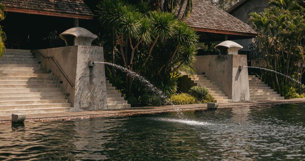 Mūsdienīga arhitektūra ar ūdens strūklakām un zaļām ainavām, kas atrodas blakus baseinam. Ideāla vieta relaksācijai un dabas baudīšanai.
