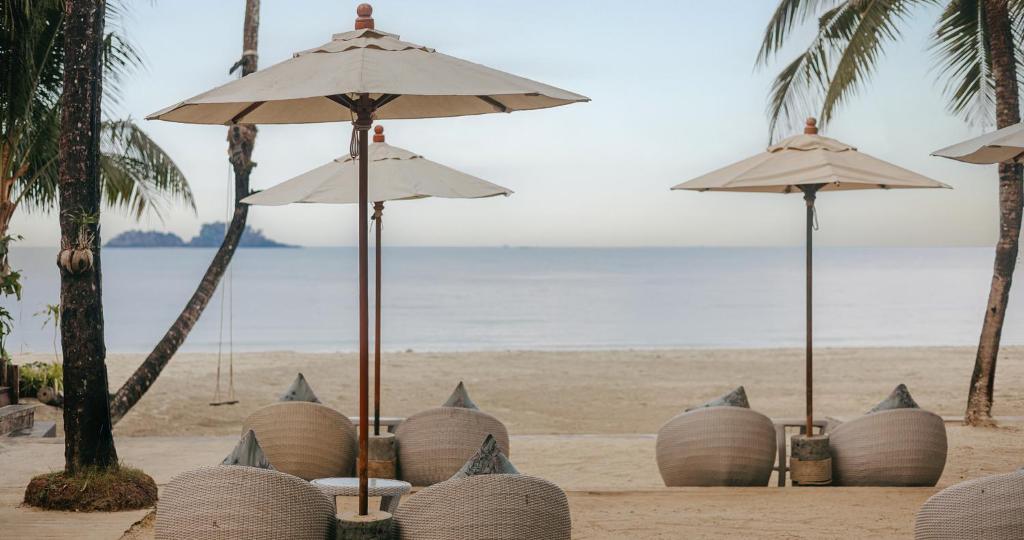 Pludmales atpūtas zona ar saulessargiem un ērtām sēdvietām, kas piedāvā mierīgu skatu uz jūru. Ideāla vieta relaksācijai un atpūtai.