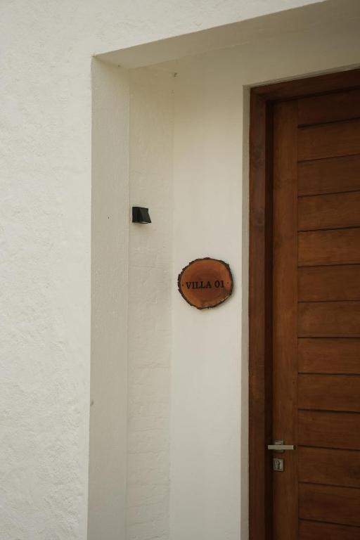 Māja ar koka durvīm un zīmi "VILLA 01", kas piestiprināta pie baltas sienas.