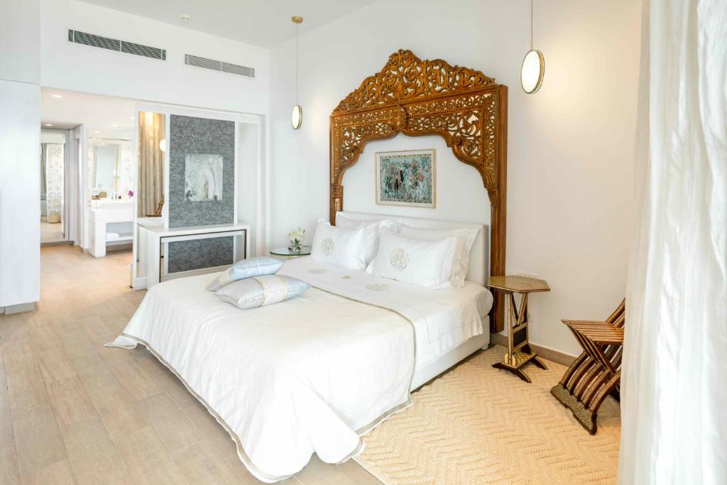 Mūsdienīgs guļamistabas interjers ar elegantu koka gultas galvu un dabīgām krāsām. Telpā ir stilīgi mēbeļu elementi un gaismas avoti, kas rada patīkamu atmosfēru.