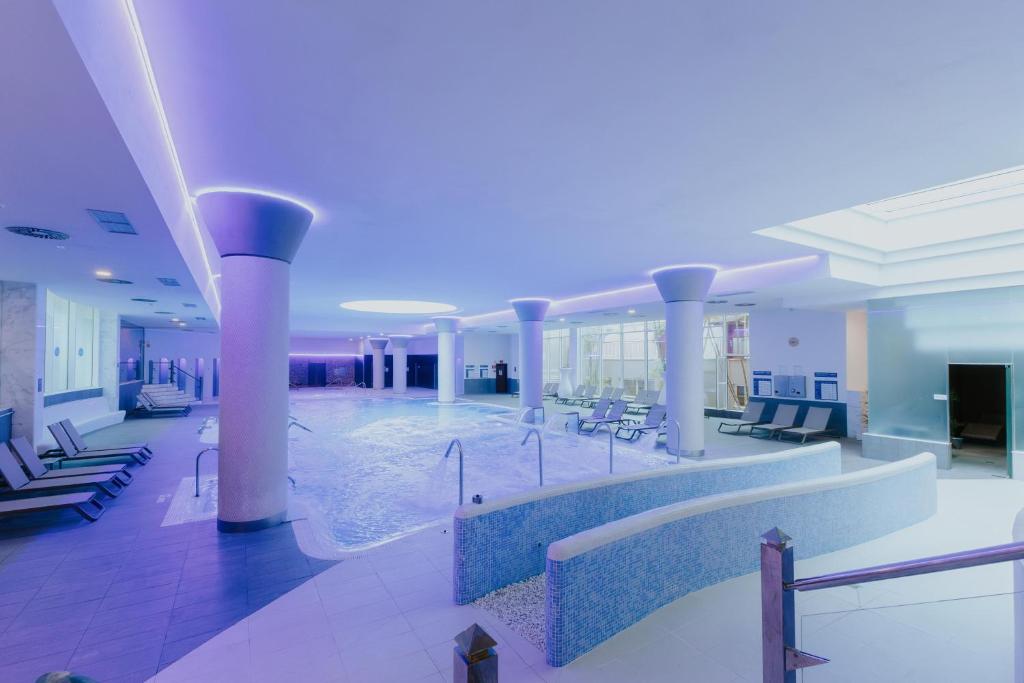 Mūsdienīgs spa ar peldbaseinu un relaksācijas zonu, apgaismots ar maigu violetu gaismu. Iekārtots ar ērtām atpūtas krēsliem un modernu dizainu.