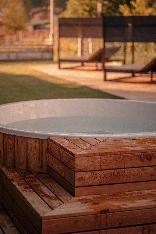 Koka terase ap apļveida baseinu, kas atrodas dārzā ar zālienu un saulainu fonu. Ideāla vieta relaksācijai un atpūtai.