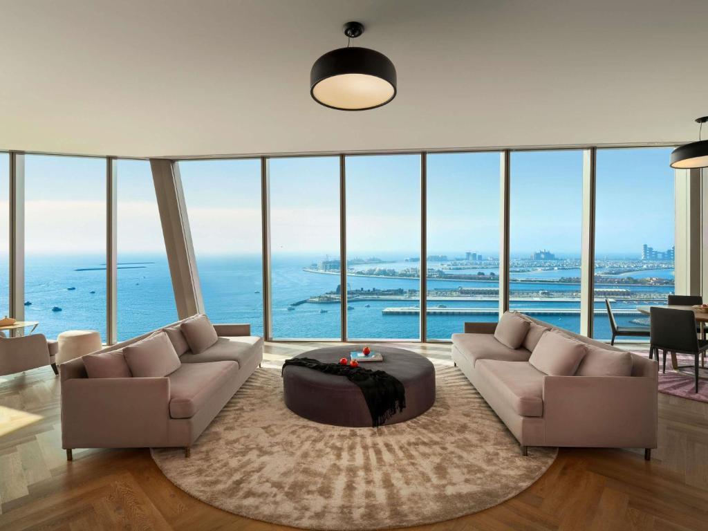 Mūsdienīgs dzīvoklis ar panorāmas skatu uz jūru, iekārtots ar elegantiem dīvāniem un modernu apgaismojumu. Telpa ir gaiša un plaša, radot komfortablu atmosfēru.