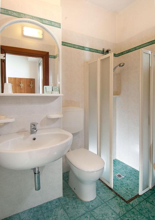 Mūsdienīgs vannas istabas interjers ar dušas kabīni, izlietni un tualeti. Svaigā un tīrā atmosfērā ar zaļiem akcentiem uz grīdas.