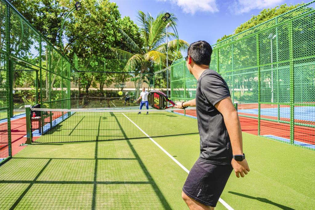 Viesi spēlē padela tenisu saulainā āra kortā Kempinski Seychelles Resort teritorijā