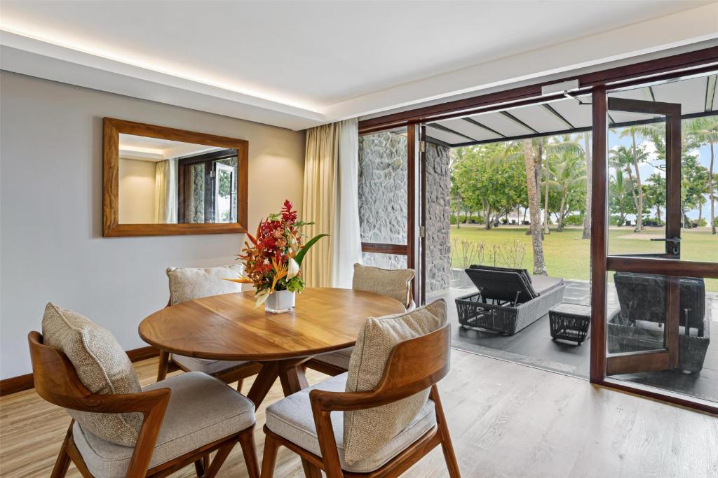 Kempinski Seychelles Resort numura ēdamzona ar koka galdu un tiešu izeju uz dārza terasi.