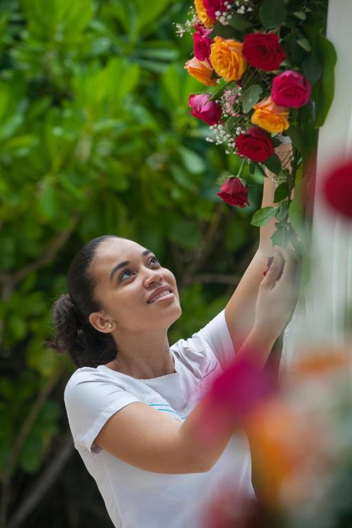 Kempinski Seychelles Resort darbiniece rūpīgi kārto krāšņu rožu kompozīciju dārza dekorācijām