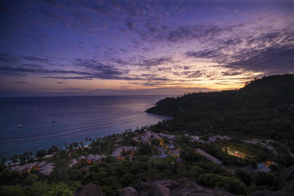 Kempinski Seychelles Resort panorāmas skats krēslas stundā ar okeānu un tropu dārziem