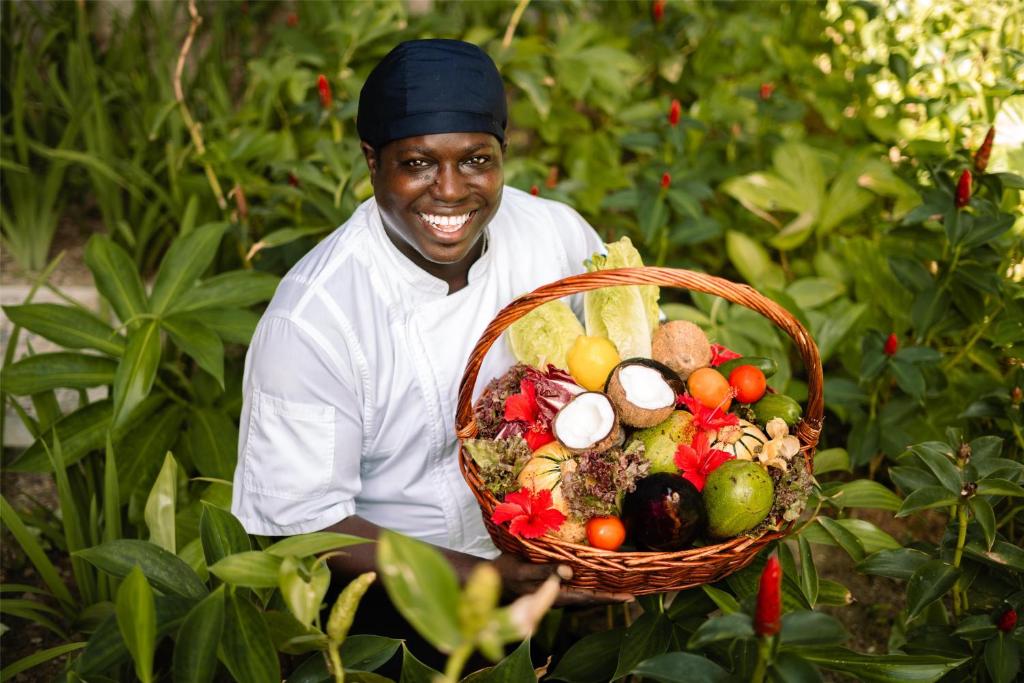 Kempinski Seychelles Resort šefpavārs dārzā ar svaigu tropu augļu un dārzeņu grozu