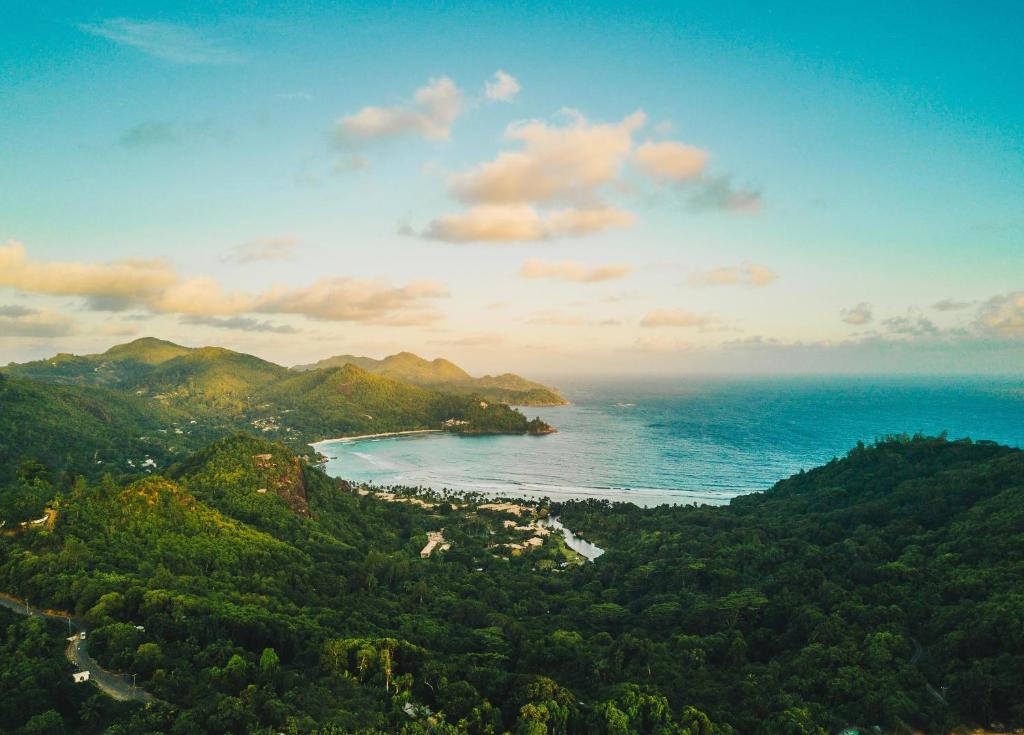 Kempinski Seychelles Resort panorāmas skats ar tropu mežiem un okeāna līci.