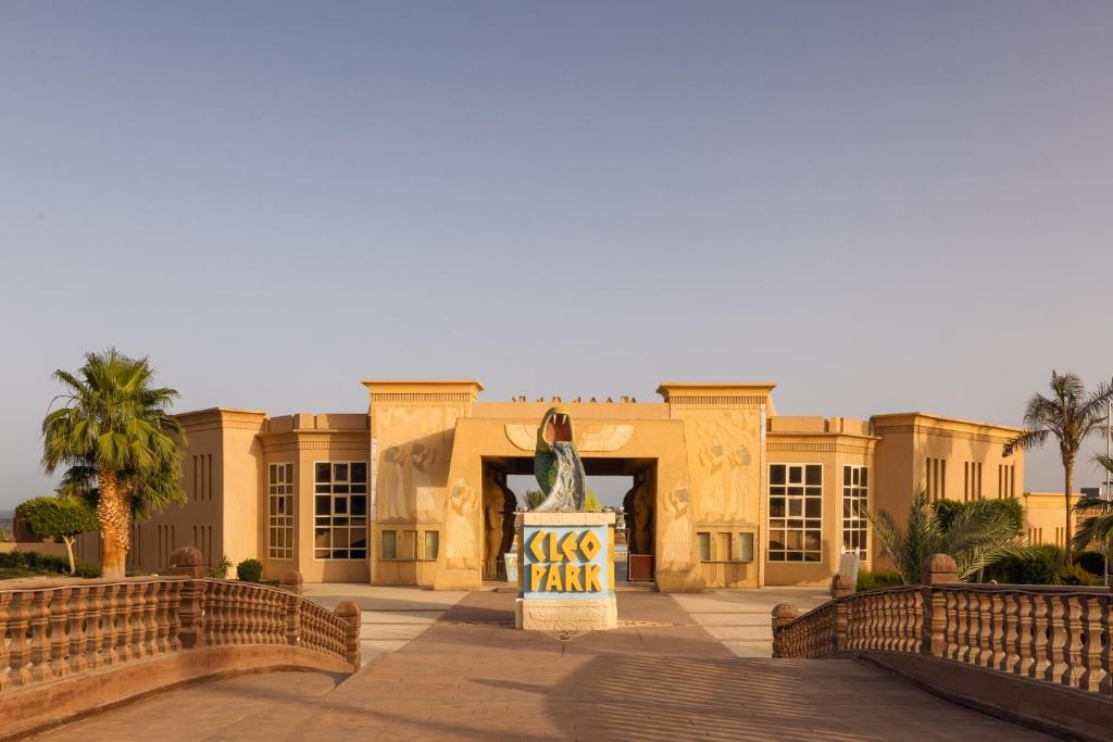 Apskatāma izklaides parka ieeja ar lielu, krāsainu zīmi un palmām apkārt. Parka arhitektūra ir unikāla un pievilcīga.