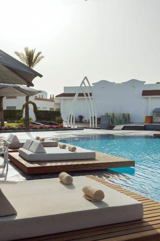 Luksusa viesnīcas baseina zona ar moderniem guļamkrēsliem un palmu kokiem, kas rada relaksējošu atmosfēru. Brīnišķīgs skats uz baseinu un apzaļumotu teritoriju.