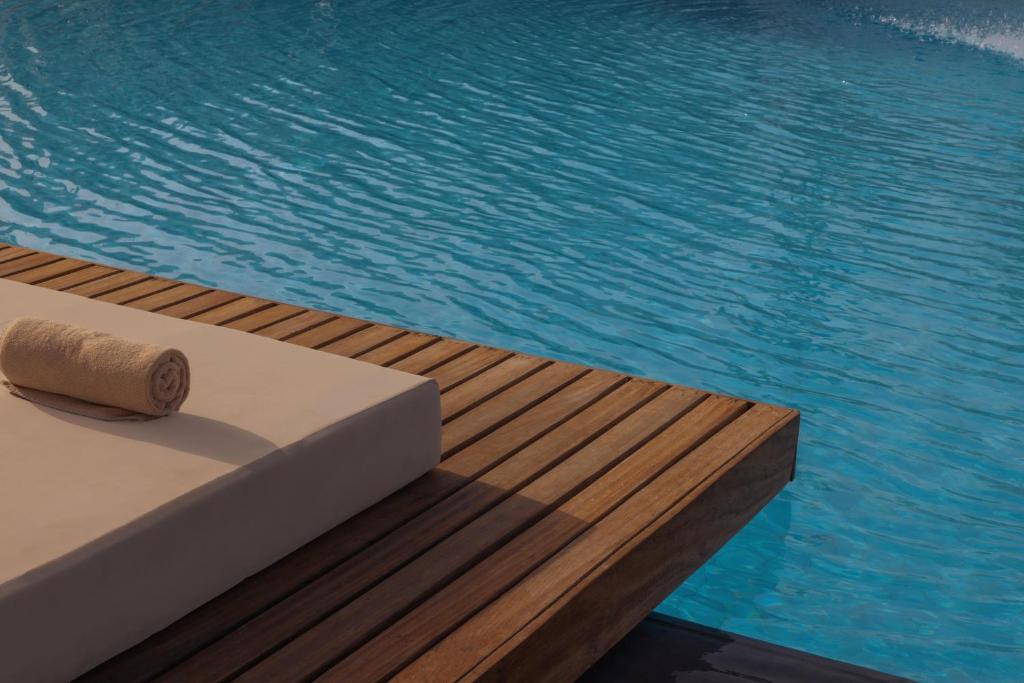 Koka terase blakus skaidram baseinam ar sarullētu dvieli. Ideāla vieta atpūtai un relaksācijai.