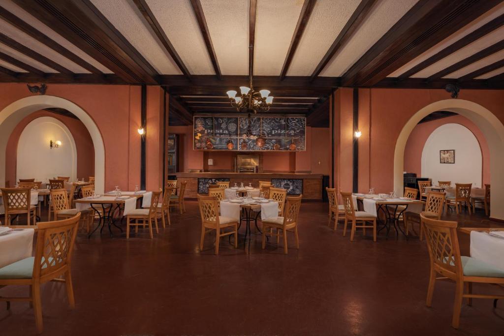 Restorāna interjers ar koka griestiem, siltām tonām un elegantām galdiem, kas iedvesmo viesus baudīt maltīti. Atmosfēra ir mājīga un aicinoša.