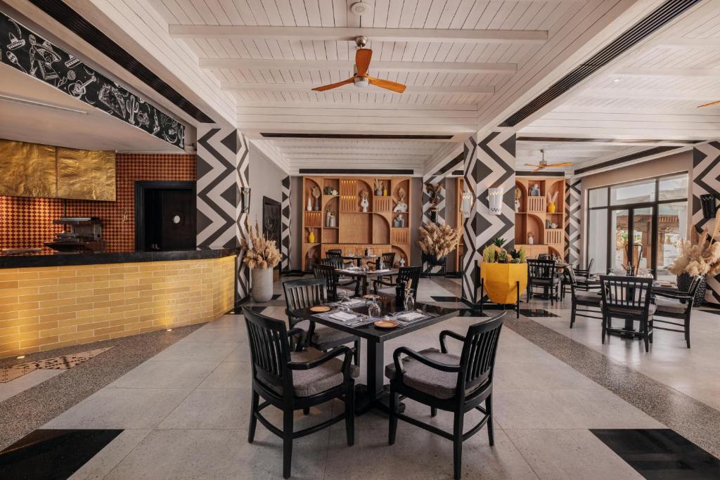 Mūsdienīgs restorāna interjers ar elegantiem melnbaltiem rakstiem, siltām krāsām un viesmīlīgu atmosfēru, kas ietver ērtus galdiņus un krēslus.