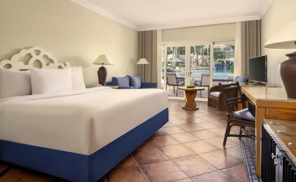 Moderns viesnīcas numurs ar plašu gultu, rakstāmgaldu un skatu uz baseinu. Interjers ir gaišs un ērts, radot relaksējošu atmosfēru.