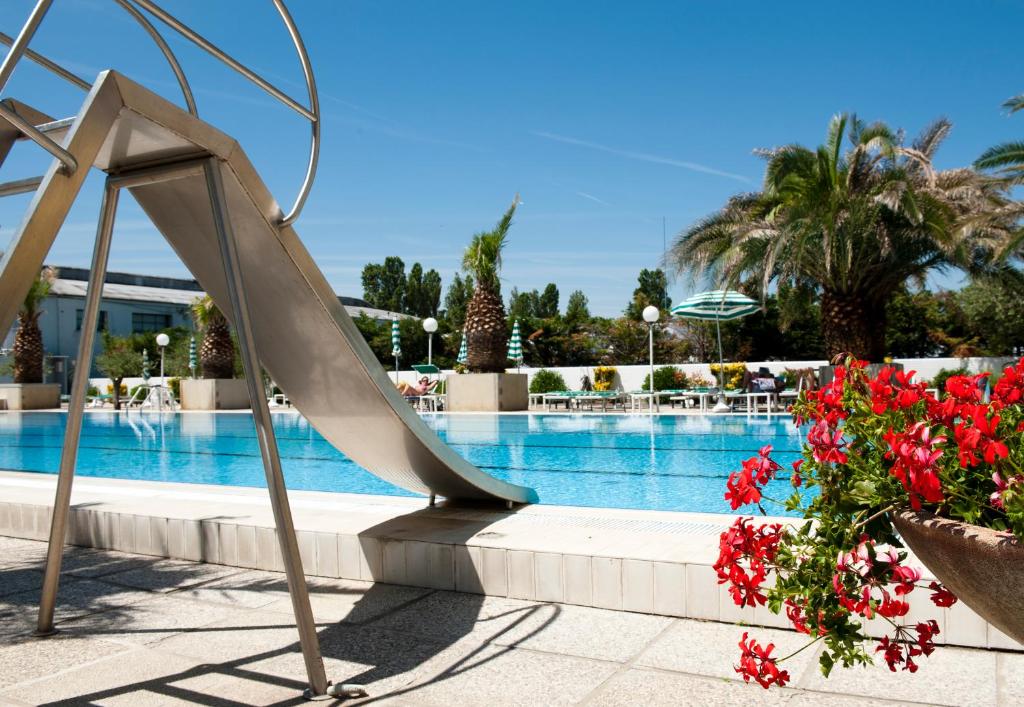 Peldbaseins ar slidkalniņu un ziedu podiem, apkārt palmām un saulei. Ideāla vieta atpūtai un izklaidei.