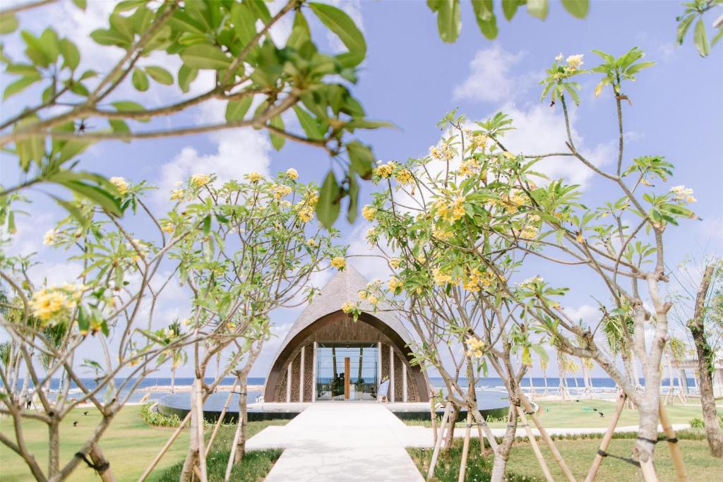 Skaista ainava ar dārzu, kurā redzami ziedoši koki un moderns arhitektūras objekts, kas atrodas pie jūras. Ideāla vieta relaksācijai un atpūtai.