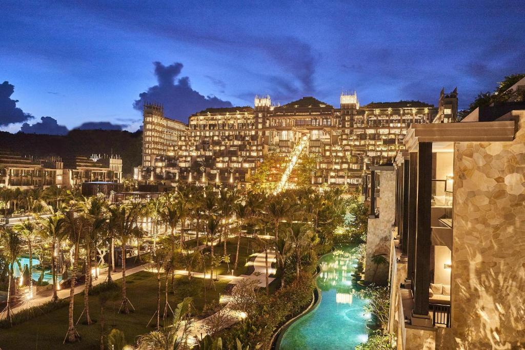 Luksusa kūrorts ar apgaismotām terasēm un zālienu, kas ieskauj peldbaseinus un dārzu, vakarā.