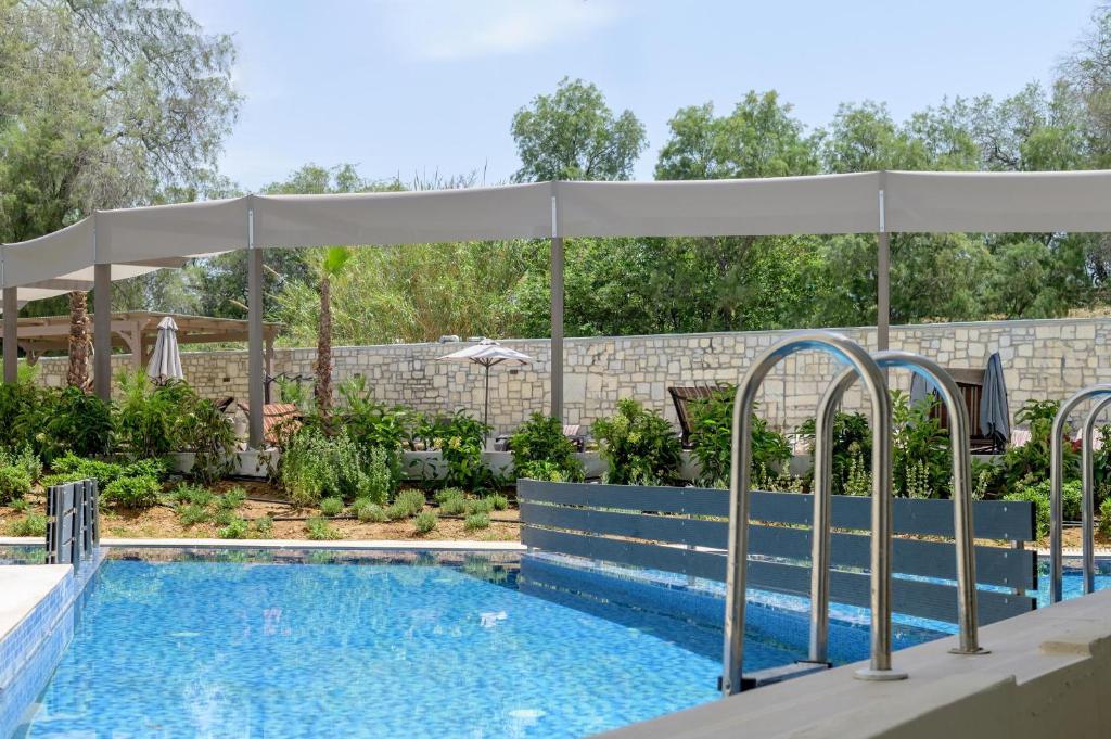 Zeus Hotels Ydoria Resort baseins ar saules nojumi un zaļām ainavām