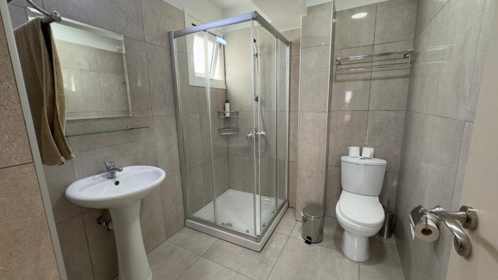 Mūsdienīga vannas istaba ar dušu, izlietni un tualeti, apdarē izmantoti neitrāli toņi. Vannas istabā ir arī spogulis un dvieļu turētājs.