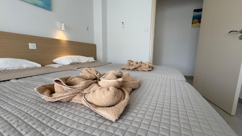 Mūsdienīga viesnīcas istaba ar diviem gultām un dekoratīvi salocītām dvieļiem uz gultām. Gaismas un istabas interjers rada patīkamu un relaksējošu atmosfēru.