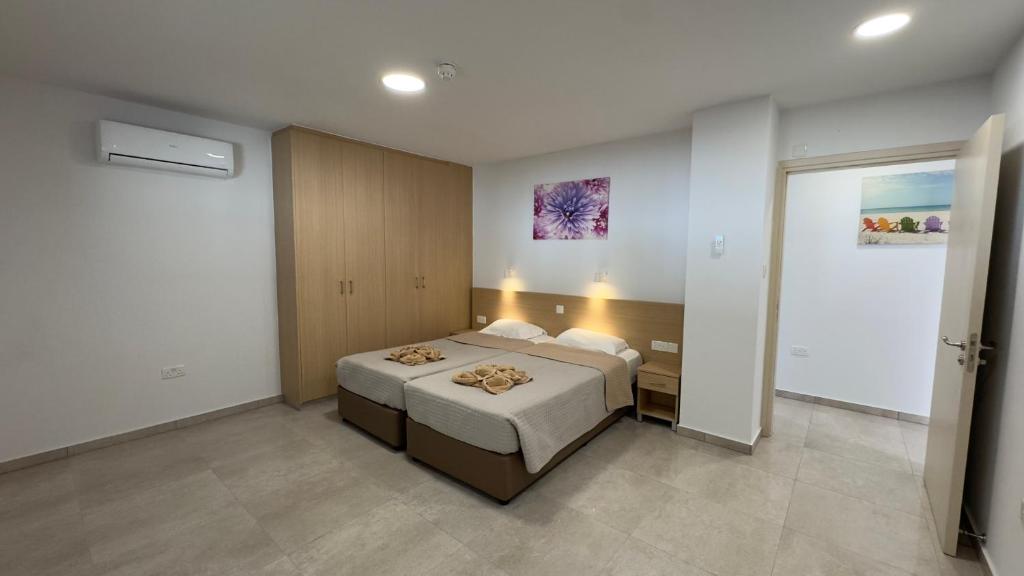 Mūsdienīga guļamistaba ar divām gultām, gaismas krāsas sienām un koka skapjiem. Telpa ir labi apgaismota un iekārtota ar gleznu uz sienas.