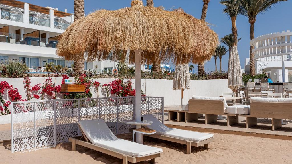 Atpūtas zona piekrastē pie Sunrise Remal Beach Resort ar sauļošanās krēsliem un salmu jumtu.