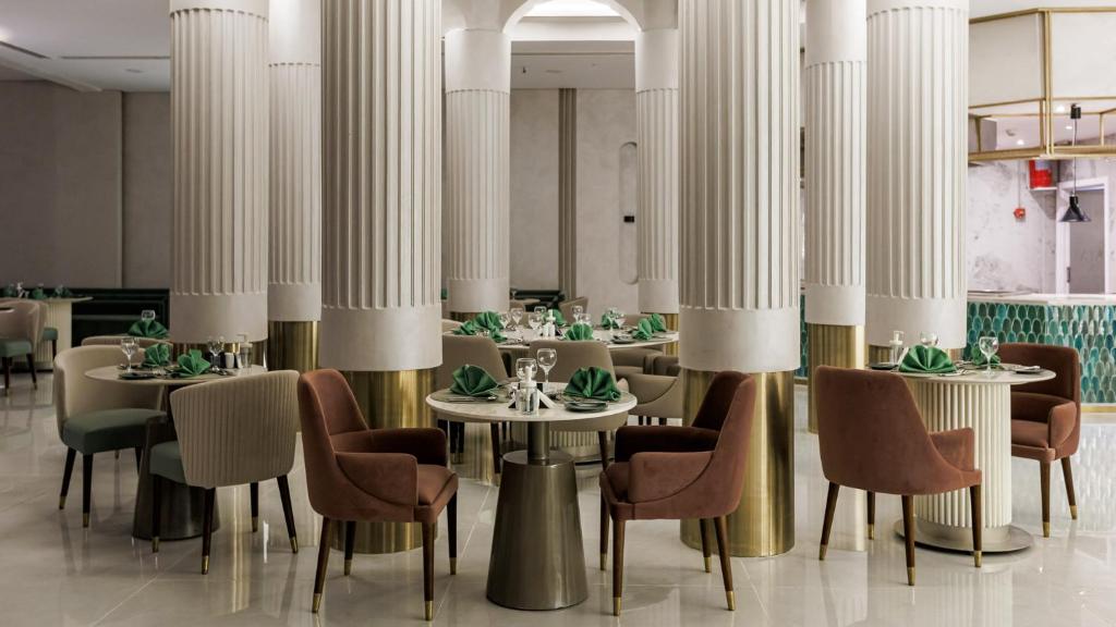 Eleganta ēdamzāle Sunrise Remal Beach Resort ar kolonnām un stilīgiem galdiem.