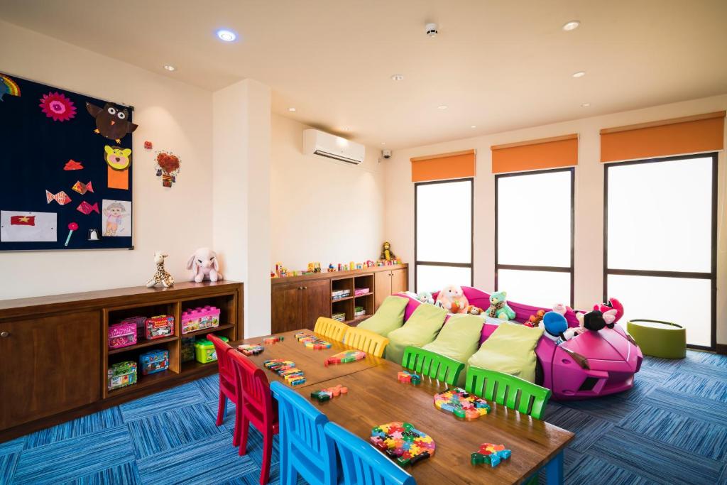 Bērnu spēļu telpa ar krāsainām mēbelēm, rotaļlietām un radošiem mākslas darbiem uz sienām, radot draudzīgu un jautru atmosfēru.