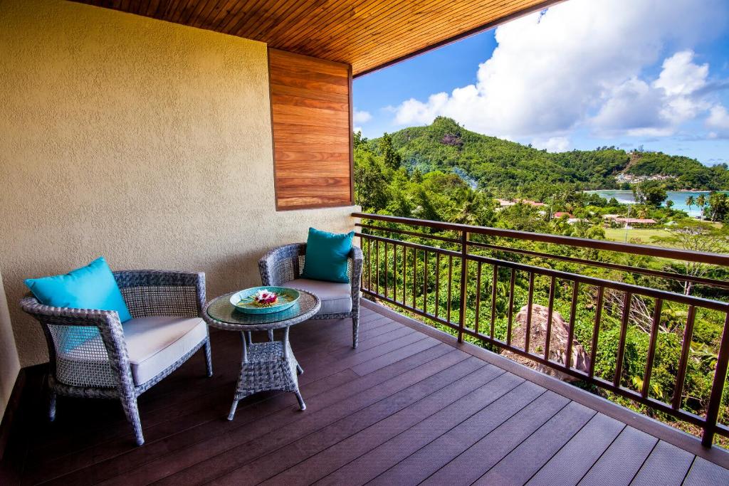 Balkons ar divām ērtiem krēsliem un galdiņu, no kura paveras skats uz zaļu kalnu ainavu un zilo jūru.