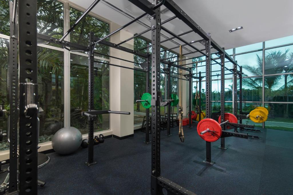 Mūsdienīgs trenažieru zāles interjers ar svaru staciju, sporta inventāru un lieliem logiem, kas nodrošina dabīgu apgaismojumu. Trenažieru zāle ir aprīkota ar dažādiem svaru diskiem un vingrošanas aprīkojumu.