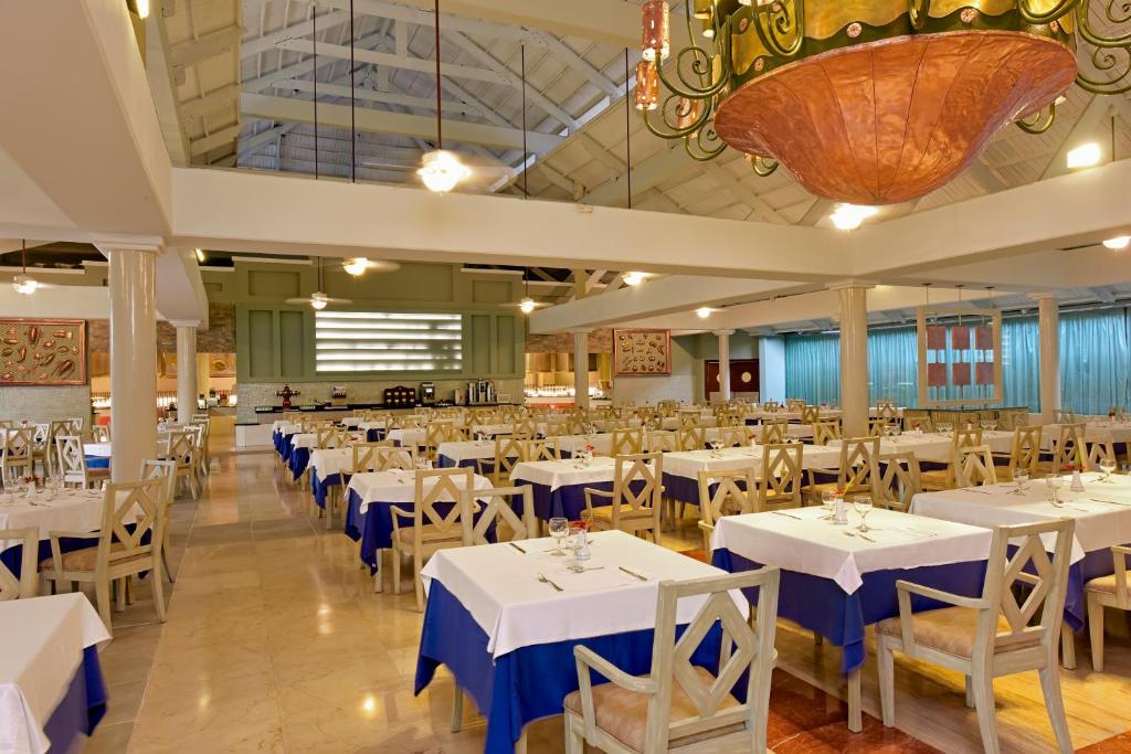 Lielas un gaišas restorāna iekštelpas ar baltām un zilu galda segumiem, kas izveidotas ērtai ēdienošanai. Gaismas ķermeņi un plašas logu ailes rada patīkamu atmosfēru.