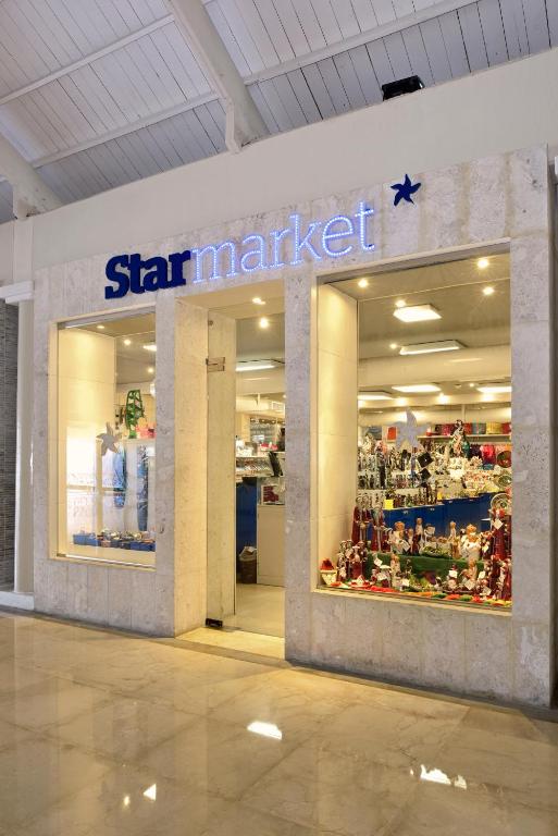Veikala "Star market" ieeja ar izgaismotiem logiem un dekorācijām, kas redzamas caur stiklu. Veikals piedāvā dažādus izstrādājumus un ir izvietots modernā telpā.